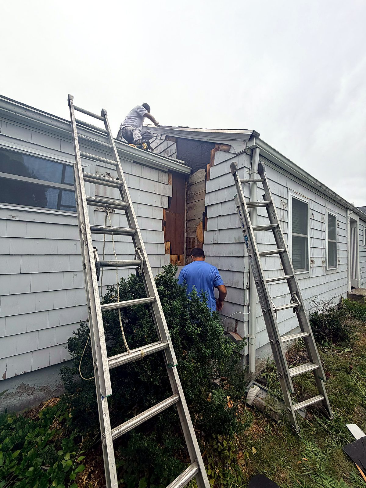 Crew working from above and from ladders at the dormer of a Worcester, MA cape with the rotted corner opened up and new sheathing going in